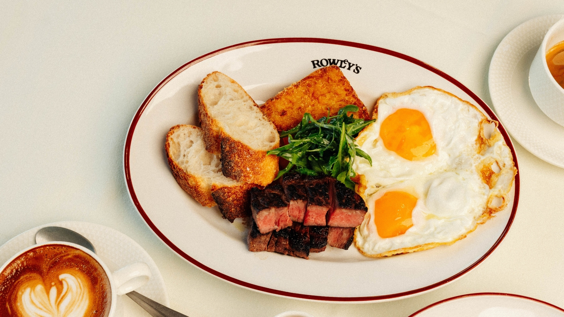 Steak and eggs breakfast plate at Rowley's Restaurant DIFC Dubai with hash browns bread salad and coffee